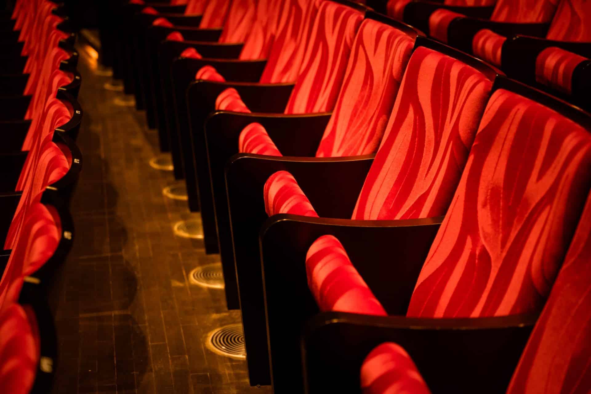 Closeup of empty red colored seats in a movie theatre with no person