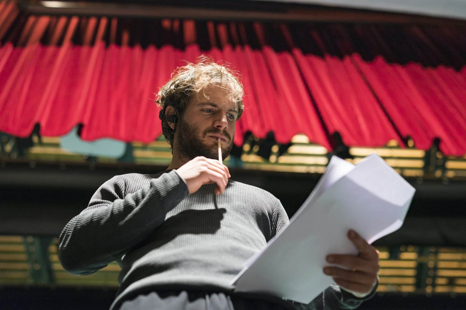 Portrait of pensive man standing on stage of theatre looking at script